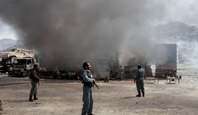 Afghan police officers watch the site of a Taliban attack last year against NATO supply trucks near the Pakistan-Afghanistan border. After more than 13 years of American bloodshed and treasure, the U.S. military will leave national security in the hands of Afghans. (Associated Press)