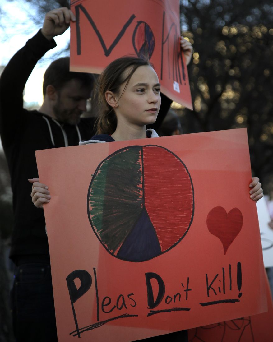 Emma Cokeley, 11, of Dallas, stands with her step father Dan Tossin, rear, as they protest with nearly 40 others outside the Dallas Convention Center where the Dallas Safari Club is holding its' weekend show and auction, Saturday, Jan. 11, 2014, in Dallas. Hunt the black rhino to save the black rhino. That's the Dallas Safari Club's approach to a fundraiser for efforts to protect the endangered species. The group hopes to raise more than $200,000 Saturday by auctioning off the right to shoot and kill a black rhinoceros in the African nation of Namibia. (AP Photo/Tony Gutierrez)