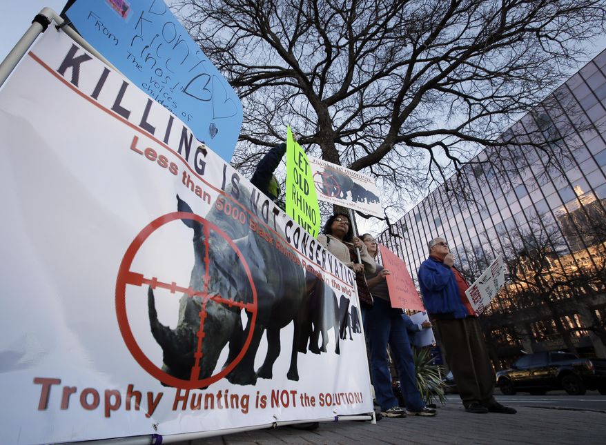 Protestors gather holding signs near the Dallas Convention Center where the Dallas Safari Club is holding it's weekend show and auction Saturday, Jan. 11, 2014, in Dallas. Hunt the black rhino to save the black rhino. That's the Dallas Safari Club's approach to a fundraiser for efforts to protect the endangered species. The group hopes to raise more than $200,000 Saturday by auctioning off the right to shoot and kill a black rhinoceros in the African nation of Namibia. (AP Photo/Tony Gutierrez)