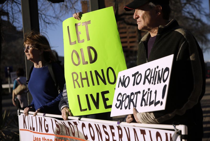 Pat Antonisse, left, of Dallas, Susan Oakey, center, of Dallas and Gary Angle, right, of Richardson, Texas, holds sign protesting outside the Dallas Convention Center where the Dallas Safari Club is holding its' weekend show and auction, Saturday, Jan. 11, 2014, in Dallas. Hunt the black rhino to save the black rhino. That's the Dallas Safari Club's approach to a fundraiser for efforts to protect the endangered species. The group hopes to raise more than $200,000 Saturday by auctioning off the right to shoot and kill a black rhinoceros in the African nation of Namibia. (AP Photo/Tony Gutierrez)