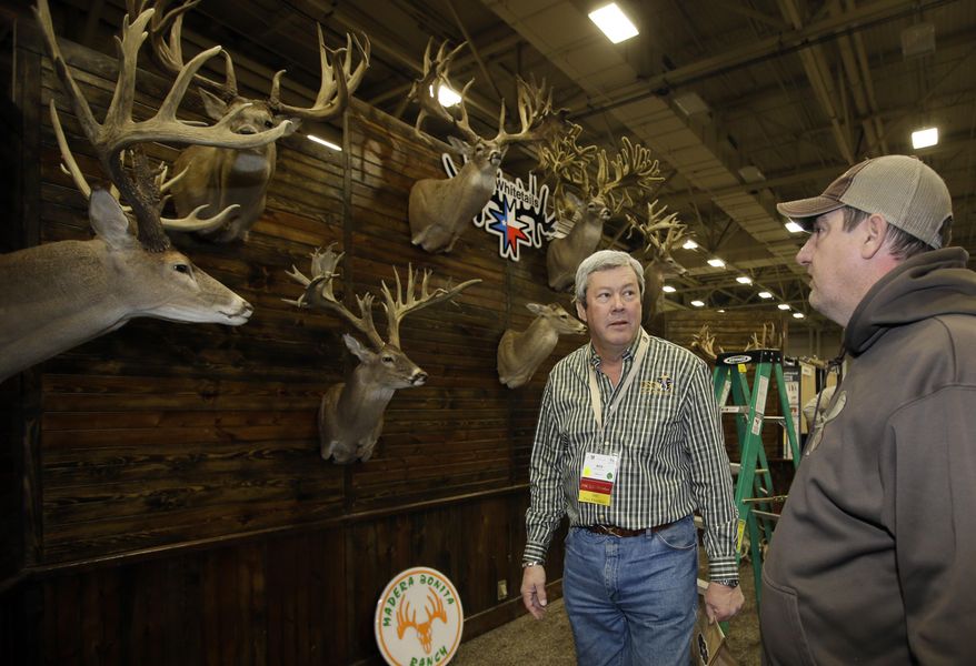 Dallas Safari Club executive director Ben Carter talks with Mike Woods of 4JM White Tails Hunting in the Dallas Exhibit Hall as set up continues for the clubs weekend show, Wednesday, Jan. 8, 2014, in Dallas. The FBI is investigating death threats made against members of the Dallas Safari Club, which intends to auction off a rare permit to hunt an endangered black rhino, an FBI spokeswoman said Wednesday. (AP Photo/Tony Gutierrez)