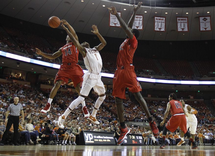 Texas' Isaiah Taylor (1) is blocked from behind by Texas Tech's Robert Turner (14) during the first half of an NCAA college basketball game, Saturday, Jan. 11, 2014, in Austin, Texas. Texas Tech's Kader Tapsoba, right, assists on the play. (AP Photo/Eric Gay)
