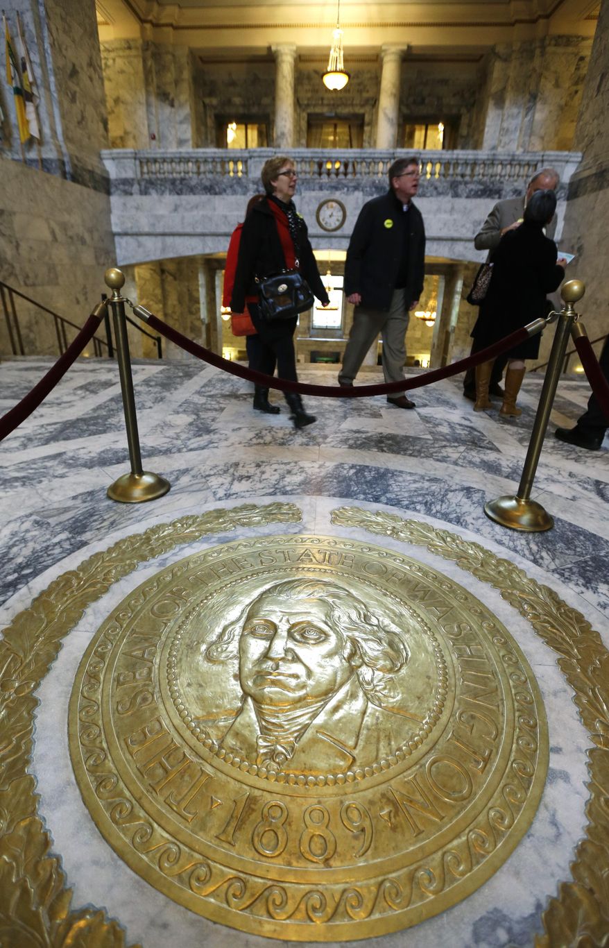 People walk past the state seal of Washington on the floor of the Capitol rotunda on the first day of the 2014 session of the Washington state Legislature, Monday, Jan. 13, 2014, at the Capitol in Olympia, Wash. (AP Photo/Ted S. Warren)