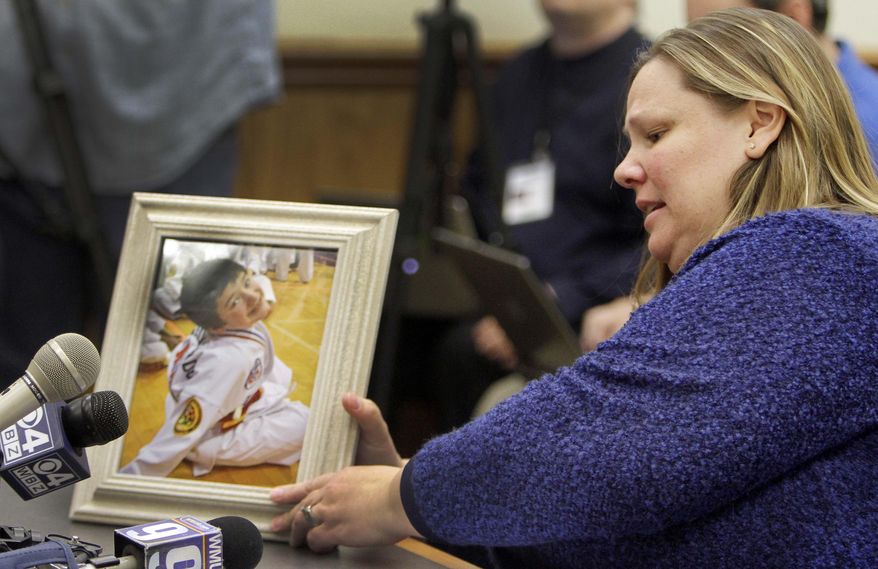 Becky Ranes places a photo of her 9-year-old son Joshua Savyon on the table before testifying Tuesday Jan. 14, 2014 at the Statehouse in Concord, N.H. before the Senate Judiciary Committee in favor of a bill that would establish domestic violence as a crime in New Hampshire. Ranes son was shot and killed by his father last year. (AP Photo/Jim Cole)
