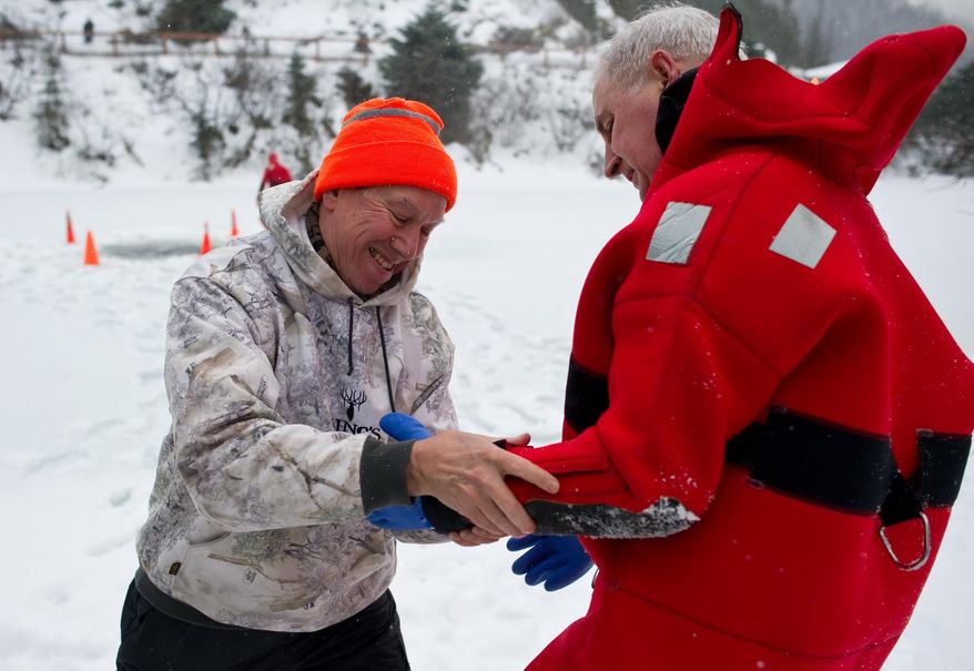 Meteorologist Joel Curtis, left, helps retired firefighter Kim Mahar with his cold water gloves before a demonstration of an ice rescue by the Capital City Fire/Rescue's rope rescue team on Saturday, Jan. 11, 2014 at the Mendenhall Glacier Visitor Center inJuneau, Ak. Nearly 150 Juneauites trekked to the Mendenhall Glacier Visitor Center recently for a lesson in surviving falling into icy waters. (AP Photo/The Juneau Empire,Michael Penn )