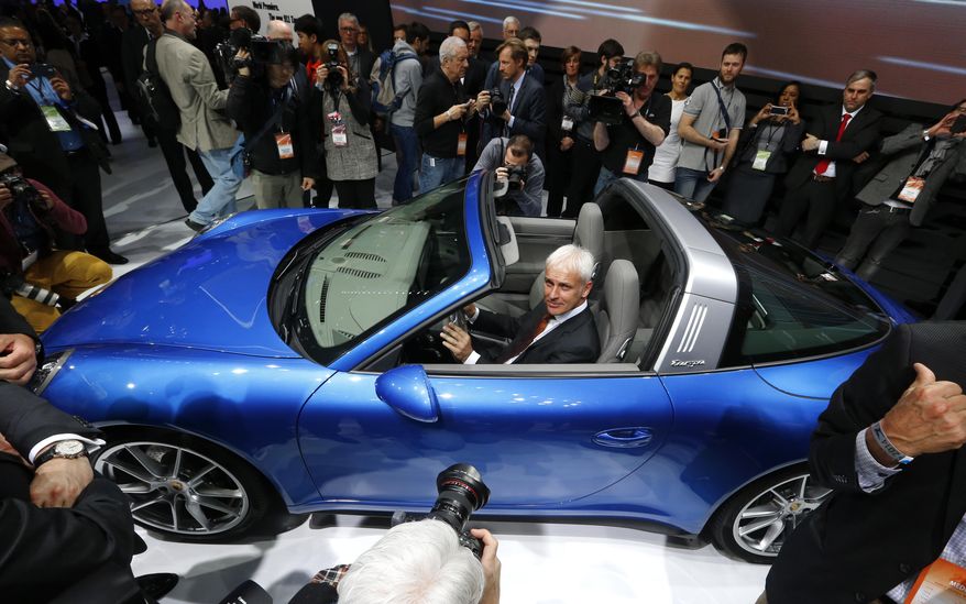 Matthias Muller, President and CEO, Porsche AG poses in the Porsche 911 Targa during media previews during the North American International Auto Show in Detroit, Monday, Jan. 13, 2014. (AP Photo/Paul Sancya)