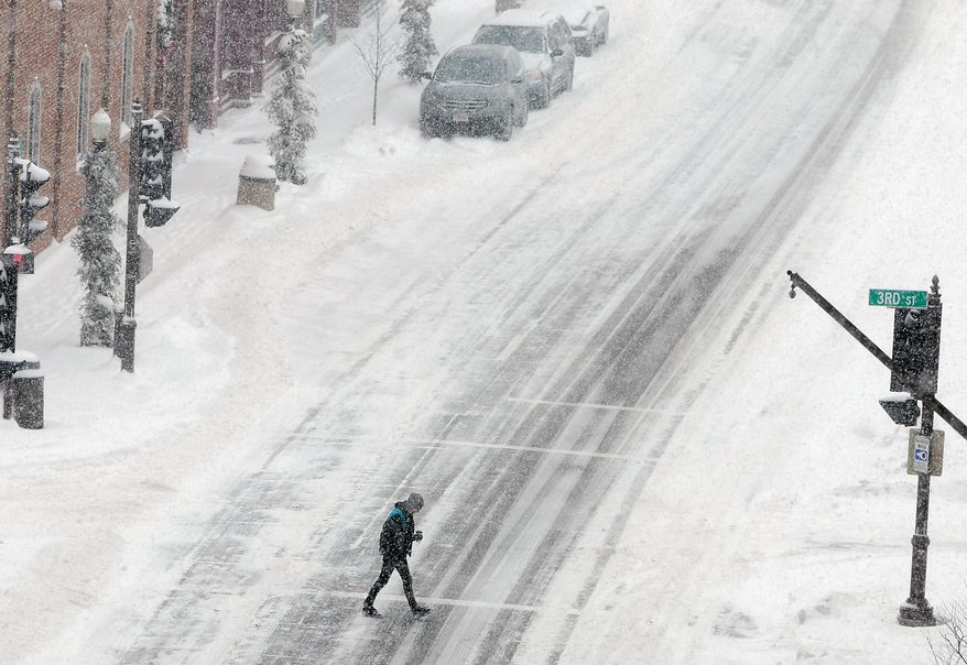 A pedestrian walks across North Third Street at Scott Street in Wausau, Wis., as heavy snow falls Tuesday, Jan. 14, 2014. (AP Photo/The Wausau Daily Herald, Joe Tamborello)