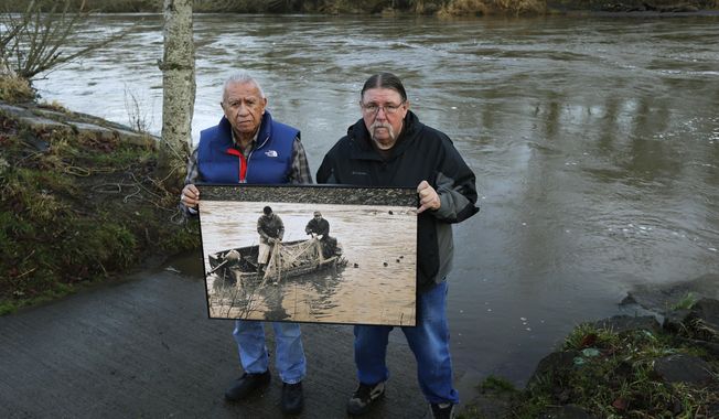 Billy Frank Jr., left, a Nisqually tribal elder who was arrested dozens of times while trying to assert his native fishing rights during the Fish Wars of the 1960s and &#x27;70s, poses for a photo Monday, Jan. 13, 2014, with Ed Johnstone, of the Quinault tribe, at Frank&#x27;s Landing on the Nisqually River in Nisqually, Wash. They are holding a photo from the late 1960s of Frank and Don McCloud fishing on the river. Several Washington state lawmakers are pushing to give people arrested during the Fish Wars a chance to expunge their convictions from the record. (AP Photo/Ted S. Warren)