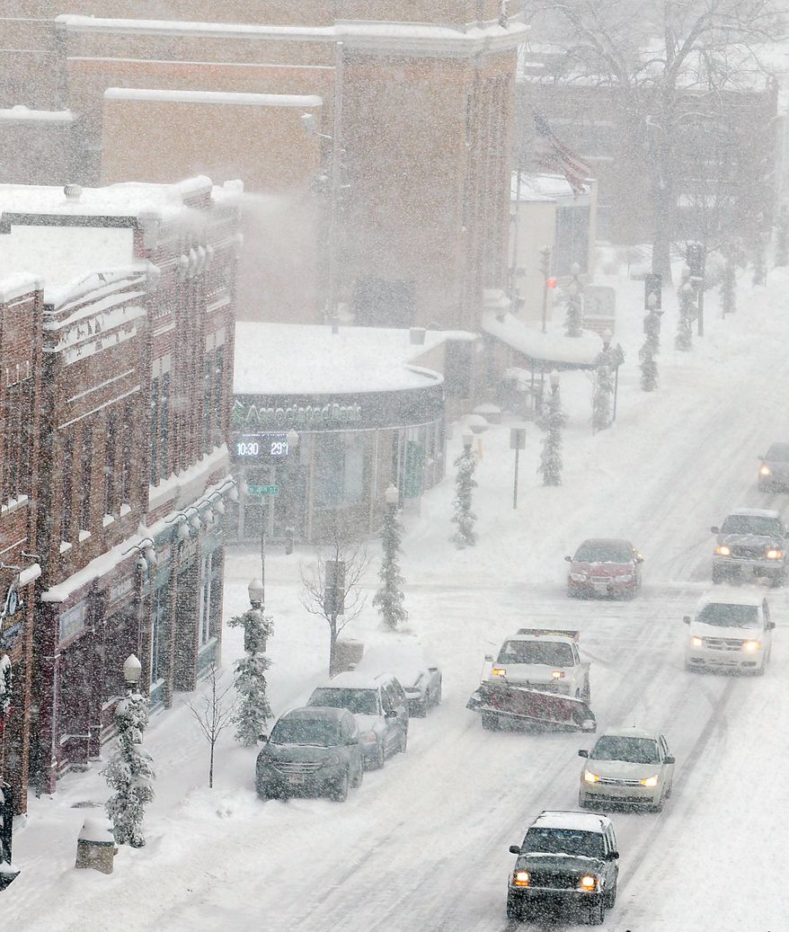 Drivers make their way west on Scott Street in Wausau, Wis., Tuesday, Jan. 14, 2014, as heavy snow falls. (AP Photo/The Wausau Daily Herald, Joe Tamborello)