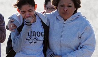 A student, left, is hugged following a shooting at Berrendo Middle School, Tuesday, Jan. 14, 2014, in Roswell, N.M. A shooter opened fire at the middle school, injuring at least two students before being taken into custody. Roswell police said the school was placed on lockdown, and the suspected shooter was arrested. (AP Photo/Roswell Daily Record, Mark Wilson)