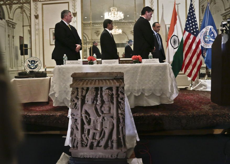 Interpol Washington Director Shawn Bray, far left, Consul General of India Dnyaneshwar Mulay, Homeland Security Investigations Associate Director James Dinkins, second from right, and Deputy Consul of India Upendra Singh Yadav, far right, stand during the playing of national anthems at a repatriation ceremony on Tuesday, Jan. 14, 2014 in New York. U.S. authorities are returning three stolen antiquities, including one of two sandstone sculptures, center, to the Indian government. (AP Photo/Bebeto Matthews)