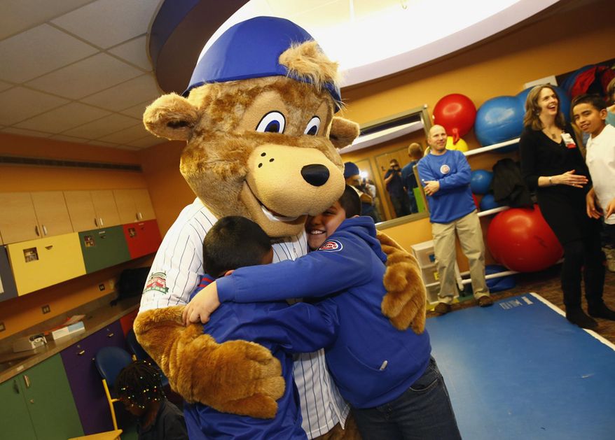 This Monday, Jan. 13, 2014 photo provided by the Chicago Cubs shows Clark, the team's first mascot, hugging children during his debut at Advocate Illinois Masonic’s Pediatric Developmental Center in Chicago. Clark, a young bear wearing a Cubs jersey and backward blue baseball cap, is named after the North Side Chicago street on which Wrigley Field is located. (AP Photo/Courtesy of the Chicago Cubs, Steve Green)