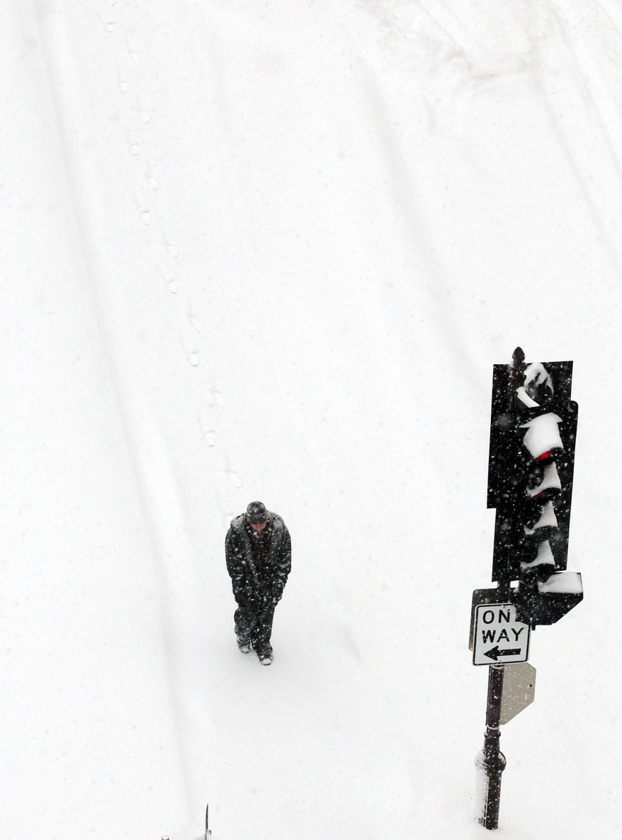 A pedestrian walks through snow on North Second Street in Wausau, Wis. as heavy snow falls Tuesday, Jan. 14, 2014. (AP Photo/The Wausau Daily Herald, Joe Tamborello)