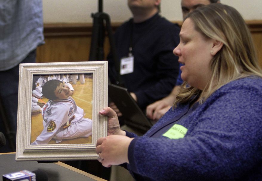 Becky Ranes places a photo of her 9-year-old son Joshua Savyon on the table before testifying Tuesday Jan. 14, 2014 at the Statehouse in Concord, N.H. before the Senate Judiciary Committee in favor of a bill that would establish domestic violence as a crime in New Hampshire. Ranes son was shot and killed by his father last year. (AP Photo/Jim Cole)