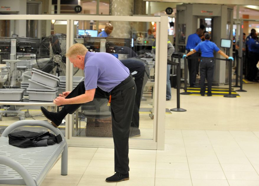 **FILE** A traveler removes his shoes at Hartsfield-Jackson Atlanta International Airport on Jan. 15, 2014. (Associated Press/Atlanta Journal-Constitution)
