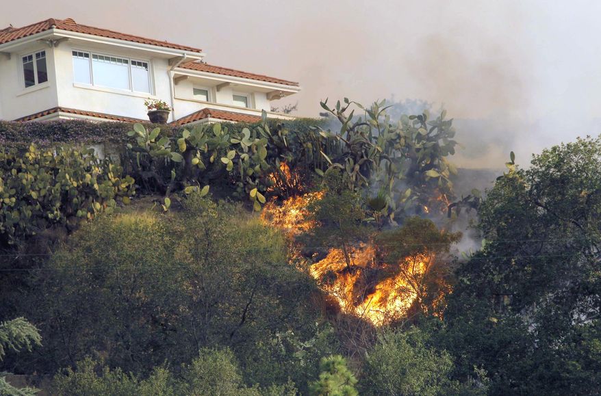 A fast moving wildfire makes it way up a hill towards a house in the hills just north of the San Gabriel Valley community of Glendora, Calif. on Thursday, Jan 16, 2014. Southern California authorities have ordered the evacuation of homes at the edge of a fast-moving wildfire burning in the dangerously dry foothills of the San Gabriel Mountains. (AP Photo/Nick Ut)