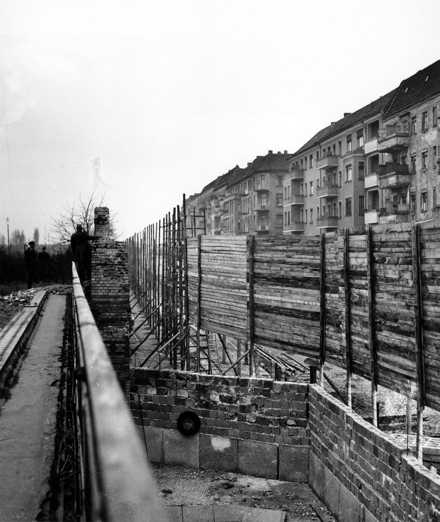 DIVIDE: West Berlin police patrol the wall, the site of frequent confrontations that threatened to erupt into major incidences. Soviet communists added a wooden fence to impede a clear view into the East Berlin zone. (Associated press photographs)