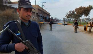 A Pakistani police officer stands guard at checkpoint on a road leading to the site of bomb explosion in Bannu, Pakistan on Sunday Jan. 19, 2014. A regular Sunday morning troop rotation going into the Pakistani tribal region of North Waziristan was shattered by an explosion that killed tens of people, mostly paramilitary troops. The Pakistani Taliban claims responsibility for placing the bomb on one of the trucks hired for the job. (AP Photo/Ijaz Muhammad)