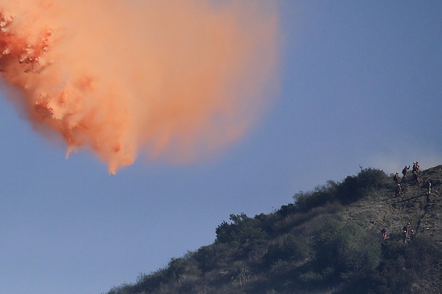 Firefighters stand along the ridge line of the San Gabriel Mountains as an aircraft drops fire retardant on Friday, Jan. 17, 2014, near Azusa, Calif. Firefighters were chasing flare-ups Friday morning in the damaging wildfire that was largely tamed but kept thousands of people from their homes in the foothill suburbs northeast of Los Angeles.(AP Photo/Jae C. Hong)