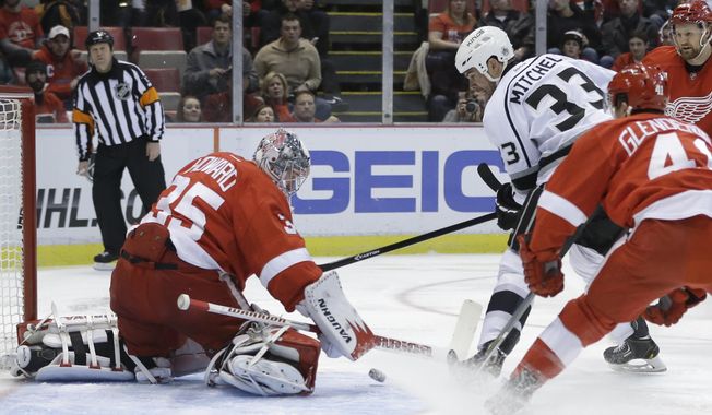 Detroit Red Wings goalie Jimmy Howard (35) deflects a shot by Los Angeles Kings defenseman Willie Mitchell (33) during the first period of an NHL hockey game in Detroit, Saturday, Jan. 18, 2014. (AP Photo/Carlos Osorio)