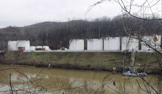 In this Jan. 13, 2014, photo, workers, left, inspect an area outside a retaining wall around storage tanks where a chemical leaked into the Elk River at Freedom Industries storage facility in Charleston, W.Va. The chemical spill that contaminated water for hundreds of thousands of West Virginians is just the latest and most high-profile case of coal polluting the nation’s waters. An Associated Press analysis of federal environmental data found chemicals and waste from the coal industry have tainted hundreds of waterways and groundwater supplies for decades, spoiling private wells, shutting down fishing and rendering streams virtually lifeless. (AP Photo/Steve Helber)