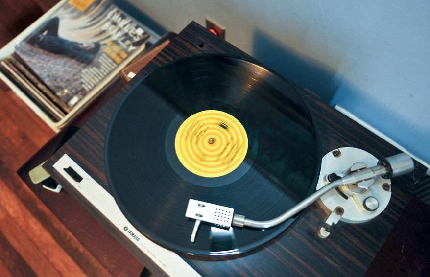 ADVANCE FOR SUNDAY JAN. 19 AND THEREAFTER - In this Monday Jan. 6, 2014 photo, a record player plays a record in the collection of Chris Vance, who lives on the East End of Charleston, W.Va. Vance and Belva Holstein are among the many twenty-somethings who are discovering the appeal of listening to music on old-fashioned vinyl records. In their apartment, where the TV should be, there’s a turntable and amplifier on a retro entertainment center, flanked by a set of 1970s stereo speakers. (AP Photo/Charleston Daily Mail, Bob Wojcieszak)