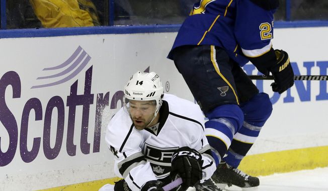 Los Angeles Kings&#x27; Justin Williams, bottom, passes the puck as he falls while St. Louis Blues&#x27; Alex Pietrangelo watches during the first period of an NHL hockey game, Thursday, Jan. 16, 2014, in St. Louis. (AP Photo/Jeff Roberson)