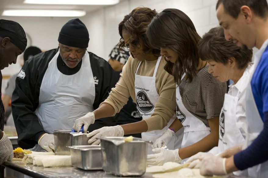 First lady Michelle Obama, center, with daughter Malia Obama and presidential adviser Valerie Jarrett, make burritos at DC Central Kitchen as part of a service project in honor of Martin Luther King, Jr. Day on Monday, Jan. 20, 2014, in Washington. Also helping were President Barack Obama and daughter Sasha Obama. (AP Photo/Jacquelyn Martin)