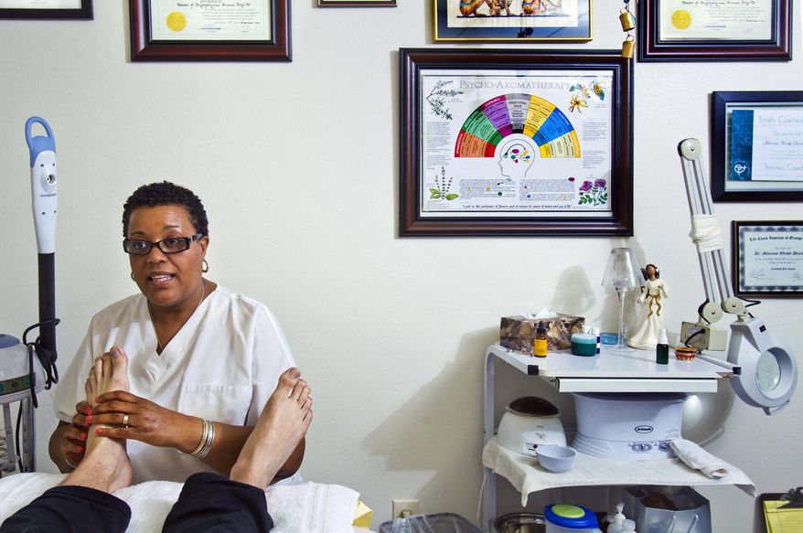 In this Friday, Jan. 17, 2014, photo, Wendy Dearborne, a reflexologist with the Adassa James Institute, gives a foot massage. Clark County officials are drafting regulations on reflexology businesses, hoping to weed scammers and prostitution out of the large but minimally regulated foot massage industry. The proposed changes set for a commission vote next month would add a new chapter in the county code to address reflexology, a practice that involves putting pressure on the feet, hands or ears to achieve a variety of health benefits. (AP Photo/The Las Vegas Sun, L.E. Baskow) LAS VEGAS REVIEW-JOURNAL OUT