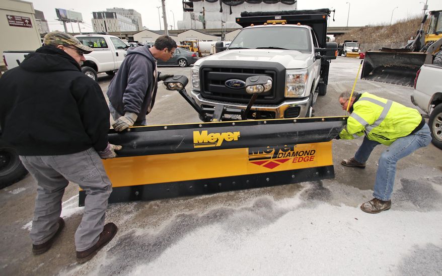 Workers from the Mass. Dept. of Conservation and Recreation put a plow on a truck in advance of an expected winter snow storm Tuesday, Jan. 21, 2014, in Cambridge, Mass. The Boston area is expected to get about a foot of snow by Wednesday evening. (AP Photo/Charles Krupa)