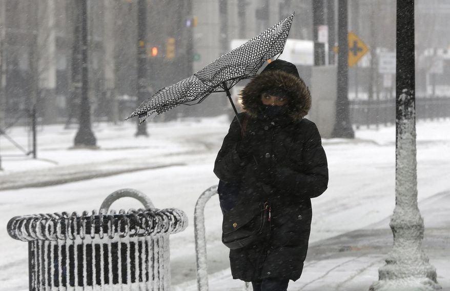 Wind flips over the canopy of an umbrella as a woman walks in gusty wind during a winter storm, Tuesday, Jan. 21, 2014, in Jersey City, N.J. The National Weather Service said the storm could bring 8 to 12 inches of snow to Philadelphia and New York City, and more than a foot in Boston. Bitterly cold air with wind chills as low as 10 degrees below zero was forecast. (AP Photo/Julio Cortez)