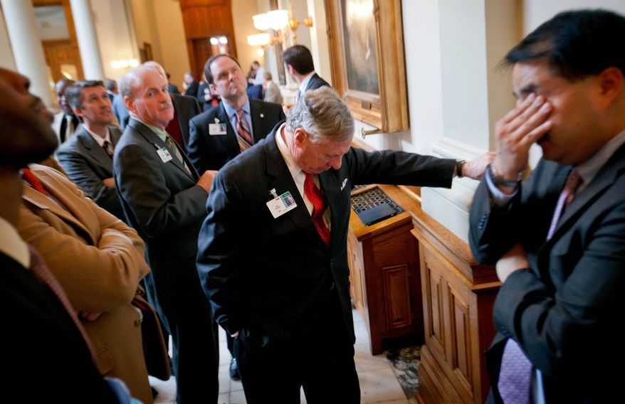 FILE- In this March 26, 2013 file photo, lobbyist Mo Thrash, center, listens with fellow lobbyists as the Senate vote on a consumer affairs bill is broadcasted in the halls of the Georgia State Capitol two days before the end of the legislative session, in Atlanta. Politicians take advantage of the last-minute chaos in Georgia's legislative session, seeking to quietly pass legislation that would invite deep scrutiny if there a chance to debate it. Now state Sen. Joshua McKoon, R-Columbus, wants to end last-minute surprises by requiring that lawmakers get at least 24 hours before voting on a bill. (AP Photo/David Goldman, File)