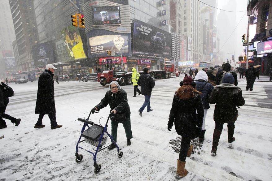 Pedestrians make their way through a snowfall, Tuesday, Jan. 21, 2014 in New York's Times Square. A storm is sweeping across the mid Atlantic states and New England. The National Weather Service said the storm could bring 8 to 12 inches of snow to Philadelphia and New York City, and more than a foot in Boston. Bitterly cold air with wind chills as low as 10 degrees below zero was forecast. (AP Photo/Mark Lennihan)