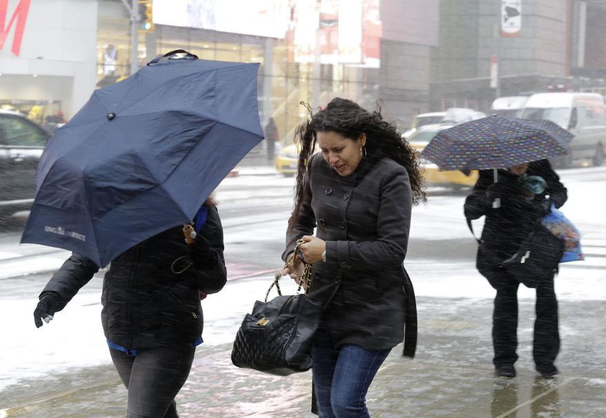 Pedestrians make their way through a snowfall, Tuesday, Jan. 21, 2014, in New York's Times Square. A storm is sweeping across the Mid-Atlantic and New England. The National Weather Service said the storm could bring 8 to 12 inches of snow to Philadelphia and New York City, and more than a foot in Boston. Bitterly cold air with wind chills as low as 10 degrees below zero was forecast. (AP Photo/Mark Lennihan)