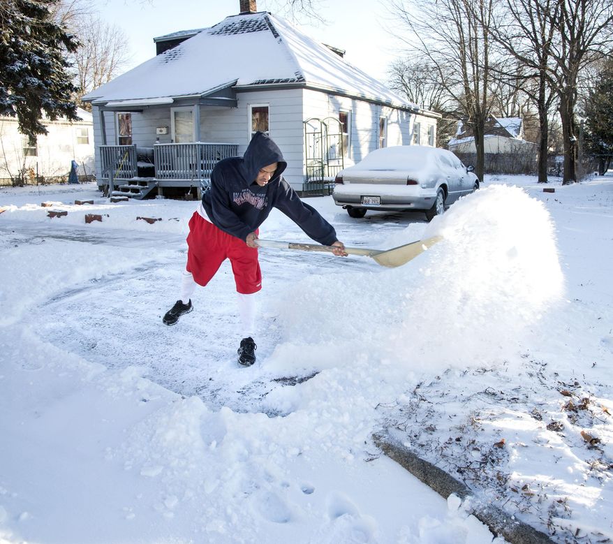 Antione Larkins shovels snow out of his driveway in Champaign, Ill., on Tuesday Jan. 21, 2014. Cold temperatures and blowing snow moved through the area overnight, closing schools in rural areas and making travel throughout the area difficult. A storm that pushed through the region late Monday and early Tuesday forced school cancellations and made commutes treacherous throughout Illinois. (AP Photo/News-Gazette, John Dixon) MANDATORY CREDIT