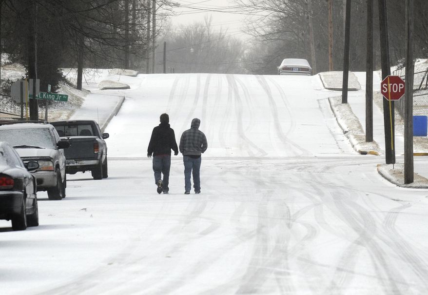 Pedestrians make their way along a snow covered S. Adams Street, Tuesday morning, Jan. 21, 2014, in Henderson, Ky. Snow and wind brought hazardous winter conditions to a large swath of Kentucky on Tuesday, creating a slow, messy morning commute and previewing a drop in temperatures to the single digits and teens as the week wears on.(AP Photo/The Gleaner, Mike Lawrence)