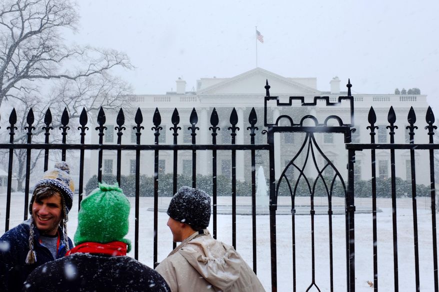 Visitors stand in front of the White House as a heavier snow begins to fall in Washington, Tuesday, Jan. 21, 2014. The Federal government was closed Tuesday morning due to weather before the first flake of snow, though heavier snow began to fall in the mid-Atlantic region by early afternoon. (AP Photo/Jacquelyn Martin)