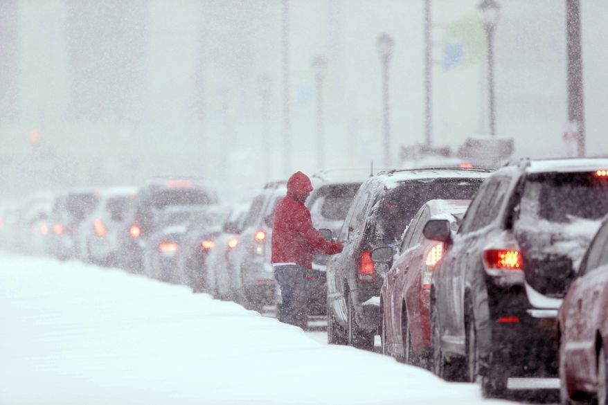 A man gets out of his car to clear the windows as traffic is at a standstill on John F Kennedy Boulevard during a winter snowstorm Tuesday, Jan. 21, 2014, in Philadelphia. A storm is sweeping across the Mid-Atlantic and New England. The National Weather Service said the storm could bring 8 to 12 inches of snow to Philadelphia and New York City, and more than a foot in Boston. (AP Photo/Matt Rourke)