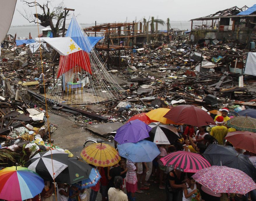 FILE - In this Dec. 25, 2013 file photo, children line up to receive a Christmas gift from volunteers near a giant lantern with the colors of the Philippine flag, in Tacloban, Philippines, a city devastated by the Nov. 8 typhoon Haiyan. Last year was tied for the fourth warmest year on record around the world. The National Oceanic and Atmospheric Administration on Tuesday released its global temperature figures for 2013. The average world temperature was 58.12 degrees (14.52 Celsius) tying with 2003 for the fourth warmest since 1880. (AP Photo/Achmad Ibrahim)