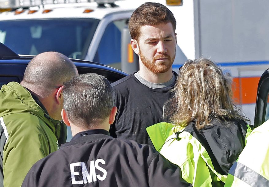 EMS personnel speak with an Cody Cousins, 23, who was detained after a shooting inside the Electrical Engineering building on the campus of Purdue University in West Lafayette, Ind. Cousins, of Warsaw, Ind., is being held in the Tippecanoe County Jail on a preliminary charge of murder, accused of shooting 21-year-old Andrew Boldt of West Bend, Wis. (AP Photo/The Journal & Courier, John Terhune)