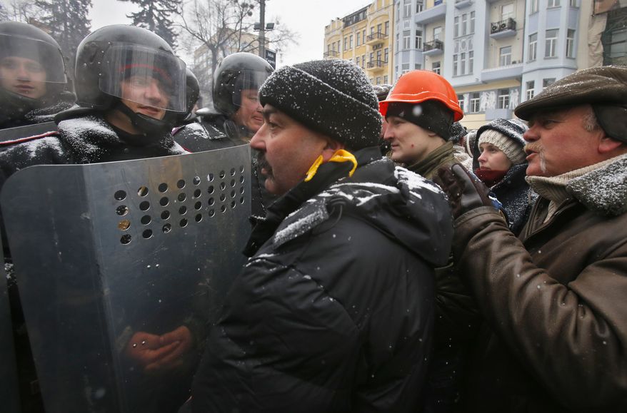 People speak to police officers as they block a street in central Kiev, Ukraine, Tuesday, Jan. 21, 2014. Opposition leader Vitali Klitschko headed for talks with the Ukrainian president on Tuesday after yet another night of violent street clashes between anti-government protesters and police. (AP Photo/Sergei Grits)