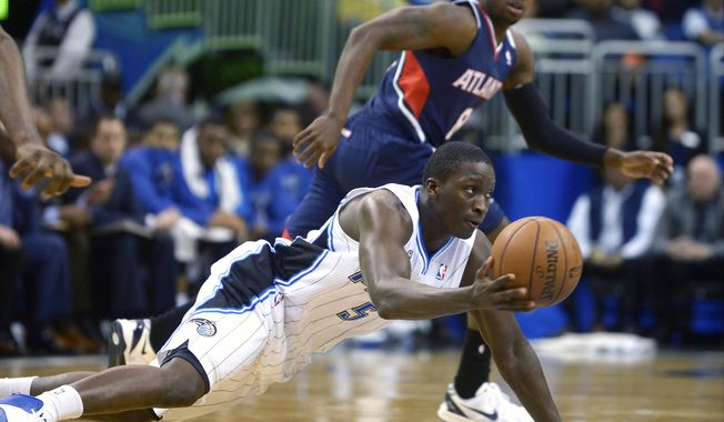 Orlando Magic shooting guard Victor Oladipo (5) passes to a teammate after gaining control of a loose ball in front of Atlanta Hawks point guard Shelvin Mack during the first half of an NBA basketball game in Orlando, Fla., Wednesday, Jan. 22, 2014. (AP Photo/Phelan M. Ebenhack)