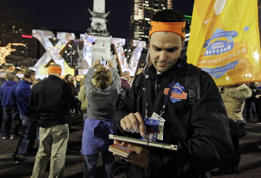 In this photo taken, Wednesday, Feb. 1, 2012, volunteer David Glenn post updates on social media for fans from Monument Circle during NFL football's Super Bowl XLVI events in Indianapolis. A year after Super Bowl XLV set a record 4,064 tweets per second, organizers are aiming to make this year's game in Indianapolis the most connected ever. They'll achieve it by dispatching dozens of volunteers to downtown streets, armed with tablets and walkie-talkies that connect them to the game's first-ever social media command center. (AP Photo/Darron Cummings)