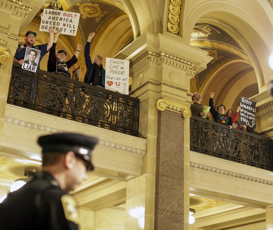 Protestors demonstrate in the state Capitol during the Governor's State of the State address Wednesday, Jan. 22, 2014, in Madison, Wis. Gov. Scott Walker made the case in his State of the State speech Wednesday that extra money collected thanks to an improving national economy should be returned as property and income tax cuts, even as some Republicans are saying his proposal goes too far. (AP Photo/Andy Manis)