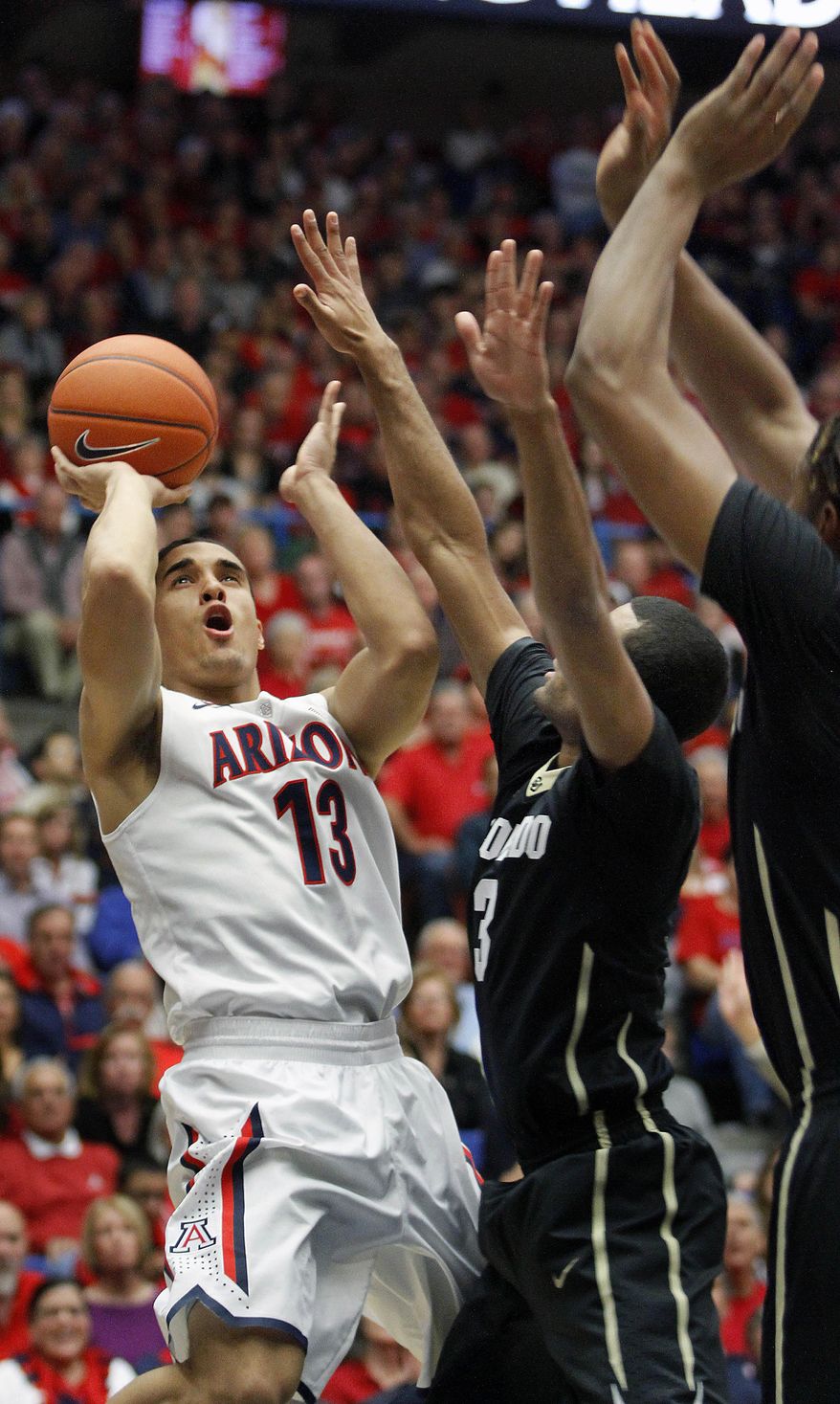 Arizona's Nick Johnson (13) shoots for two against the defense of Colorado's Xavier Talton (3) and Xavier Johnson, far right, in the first half of an NCAA college basketball game, Thursday, Jan. 23, 2014 in Tucson, Ariz. (AP Photo/John Miller)