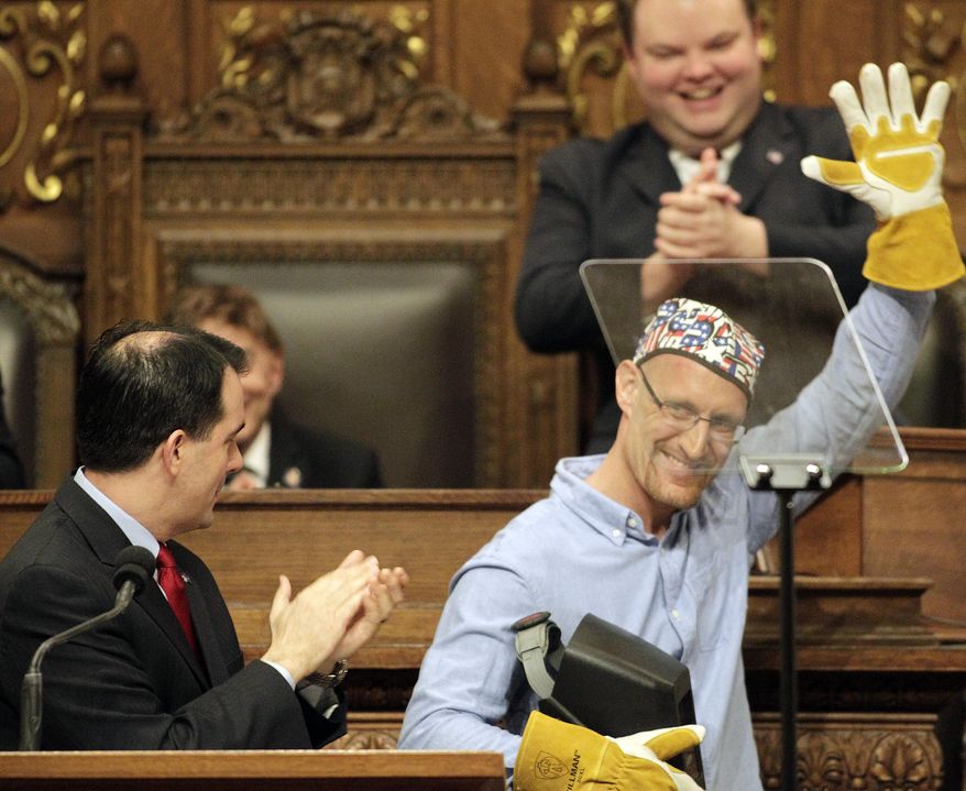 Wisconsin Gov. Scott Walker applauds as Chris Barber of Two Rivers,wis., a welder at Ariens Company, leaves the podium during Walker's State of the State address at the state Capitol in Madison, Wis., Wednesday, Jan. 22, 2014. (AP Photo/Wisconsin State Journal, M.P. King)