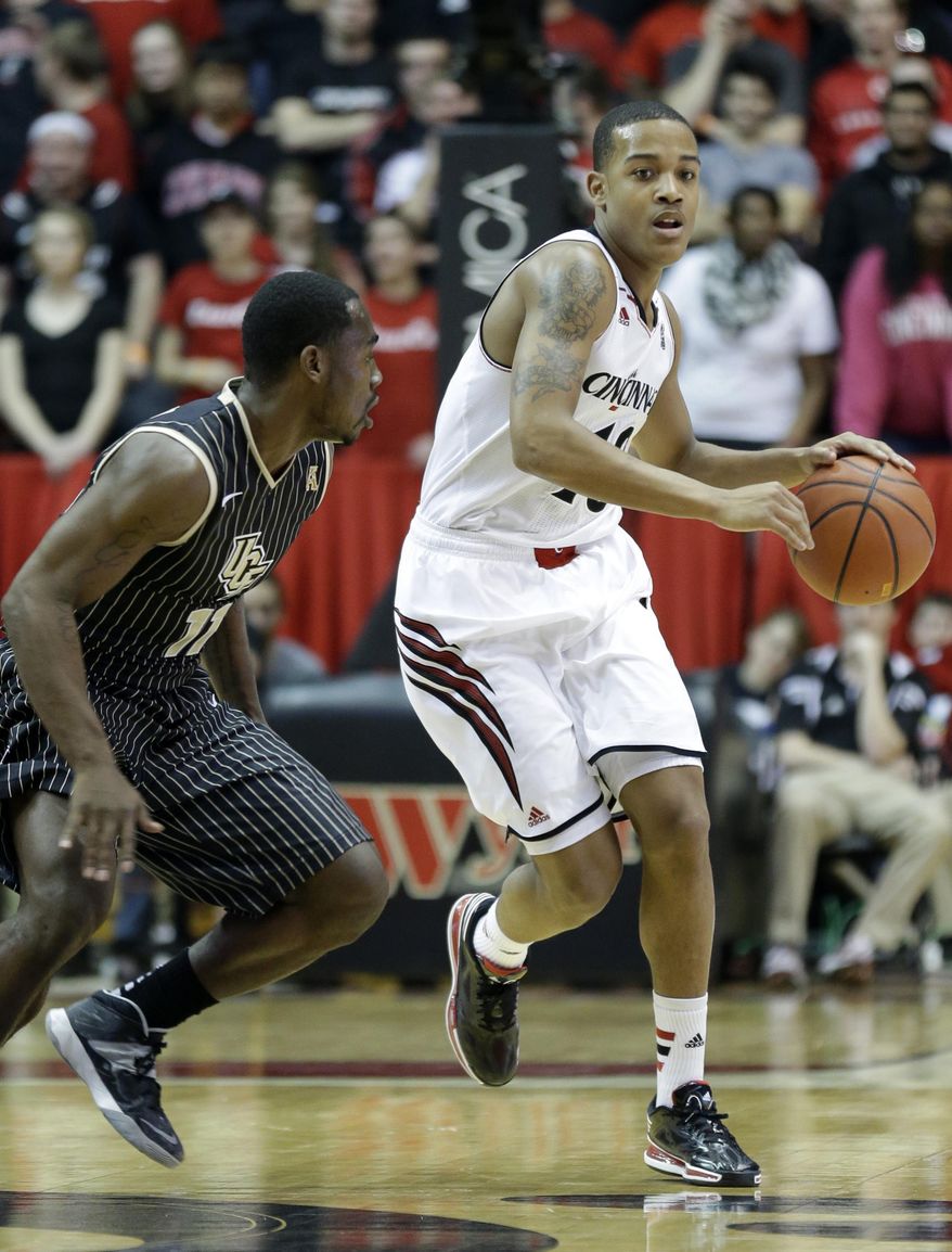 Cincinnati guard Troy Caupain, right, brings the ball up court against Central Florida guard Calvin Newell in the first half of an NCAA college basketball game, Thursday, Jan. 23, 2014, in Cincinnati. (AP Photo/Al Behrman)
