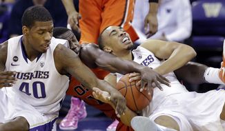 Oregon State&#39;s Daniel Gomis, center, is trapped between Washington&#39;s Shawn Kemp Jr. (40) and Andrew Andrews during the first half of an NCAA college basketball game Saturday, Jan. 25, 2014, in Seattle. (AP Photo/Elaine Thompson)