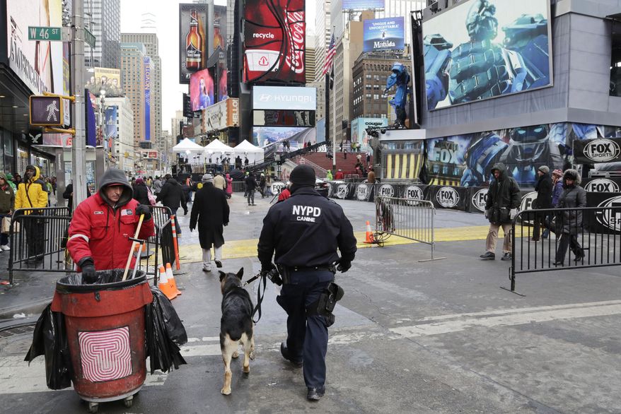 An NYPD officer patrols with a dog, Sunday, Jan. 26, 2014 in New York's Times Square. (AP Photo/Mark Lennihan)