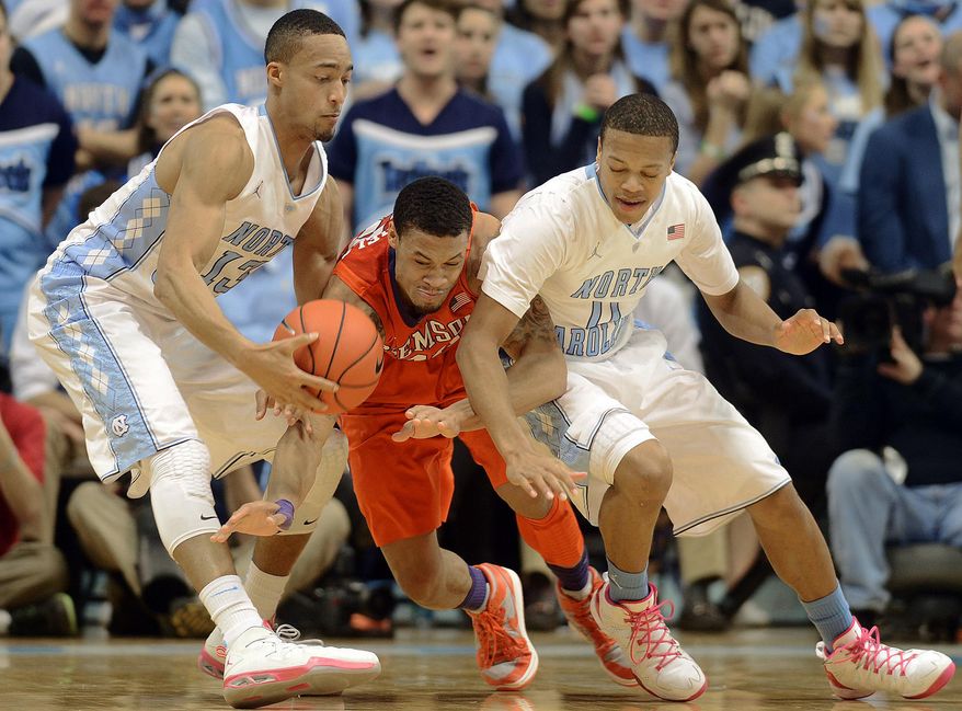 North Carolina's J.P. Tokoto and Nate Britt battle Clemson's K.J. McDaniels, center, for a loose ball during an NCAA college basketball game on Sunday, Jan. 26, 2014, in Chapel Hill, N.C. (AP Photo/The Herald-Sun, Bernard Thomas)